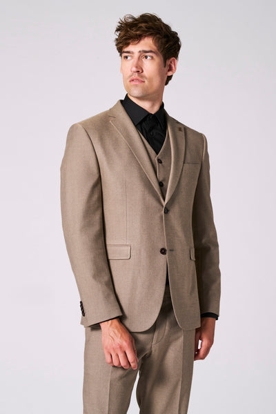 Beige blazer van Le Fabuleux Marcel uit Brussel, gedragen over een zwart overhemd met een bijpassend vest.