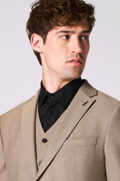 Beige blazer van Le Fabuleux Marcel uit Brussel met een decoratieve knoopsgat op de revers, gedragen over een zwart overhemd.