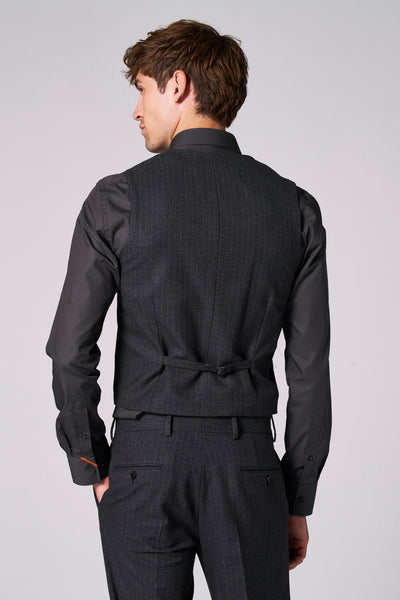 Gilet brun par Le Fabuleux Marcel de Bruxelles, motif à carreaux, porté avec une chemise noire et un pantalon assorti, vue de dos.
