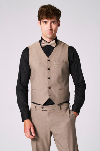 Beige gilet van Le Fabuleux Marcel de Bruxelles, met verstelband aan de achterkant en gedragen over een zwart overhemd en een bijpassende broek.