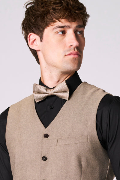 Beige gilet van Le Fabuleux Marcel de Bruxelles met een zwart overhemd en een gestructureerde vlinderdas.