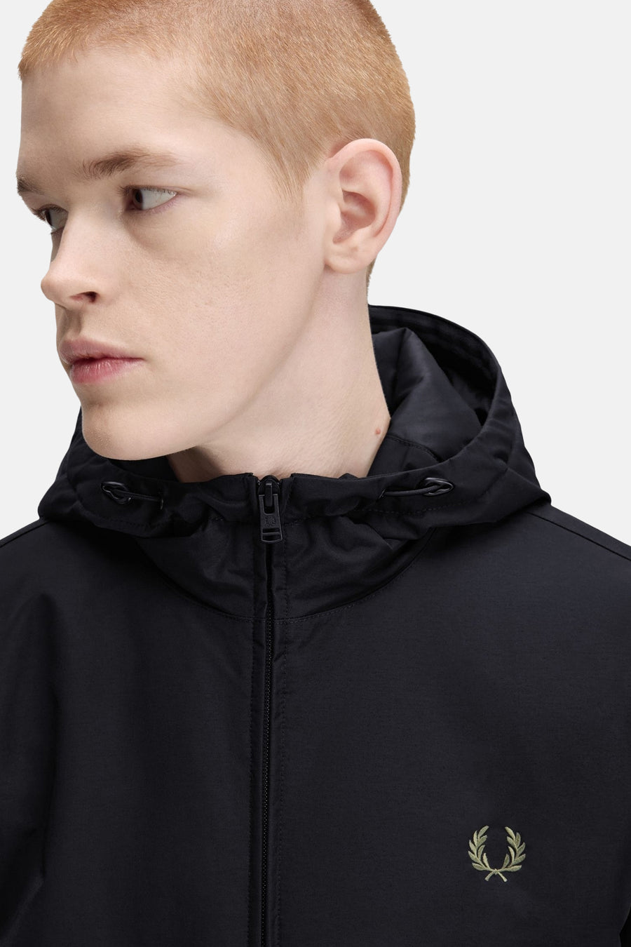 Black waterproof hooded rain jacket with front zipper and olive green embroidered laurel wreath logo, side view close-up