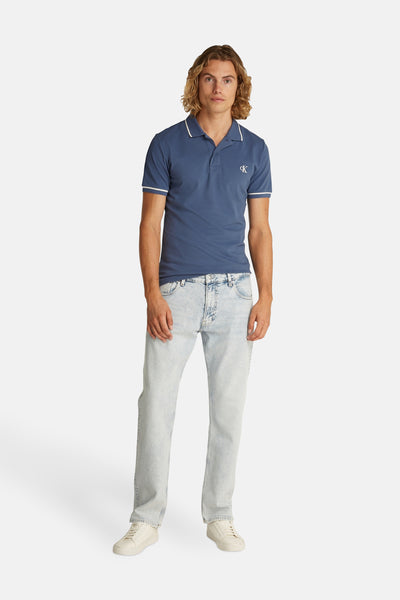Marineblaues Kurzarm-Poloshirt von Calvin Klein, getragen mit ausgewaschener Jeans und weißen Turnschuhen.