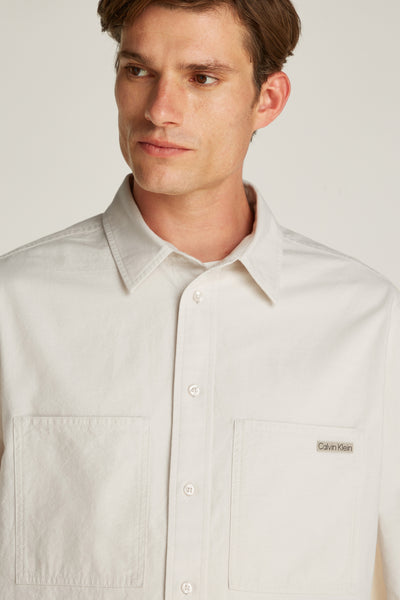 Chemise à manches longues écrue de Calvin Klein avec poches plaquées sur la poitrine.