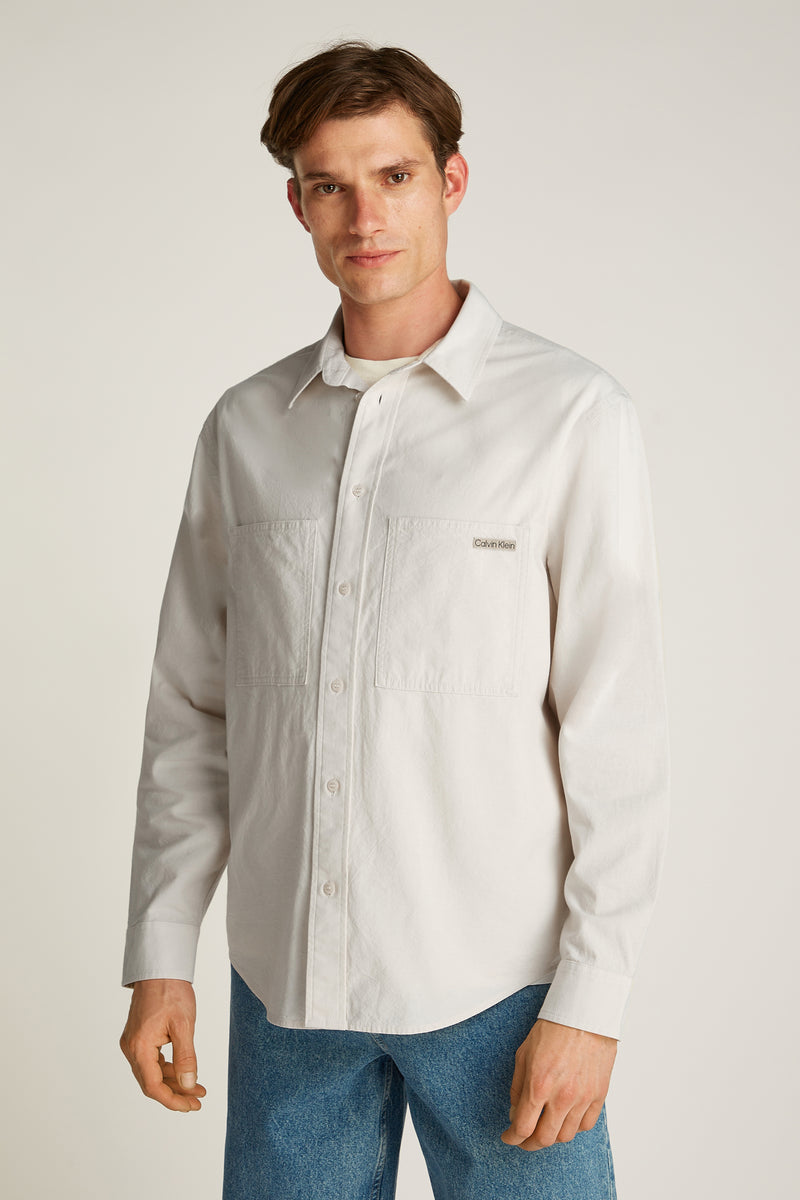 Chemise à manches longues écru de Calvin Klein, avec deux poches poitrine boutonnées et coupe décontractée.