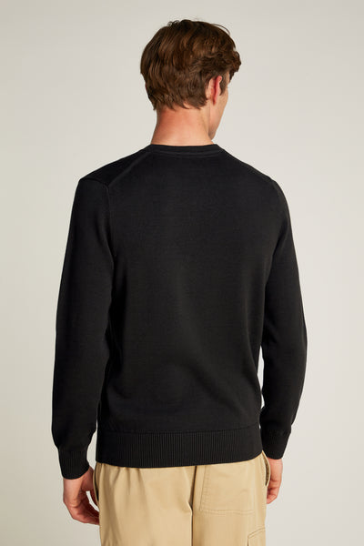 Pull col rond noir de Calvin Klein, vue arrière, porté avec un pantalon cargo beige.
