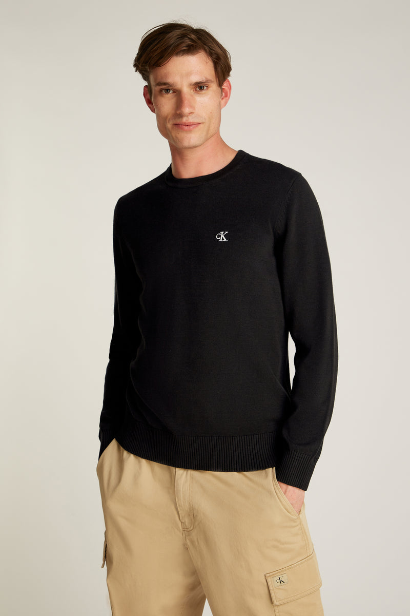 Pull col rond noir de Calvin Klein, porté avec un pantalon cargo beige.