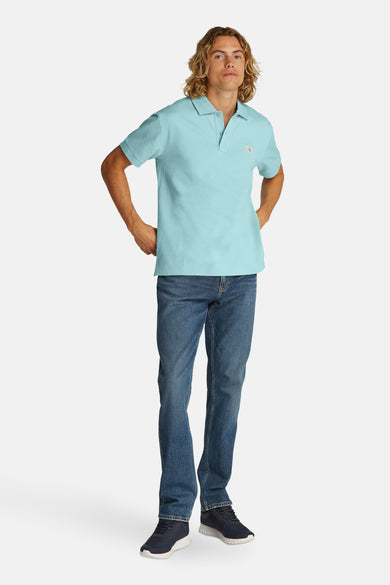 Turquoise poloshirt met korte mouwen van Calvin Klein, gedragen met een spijkerbroek en sneakers.