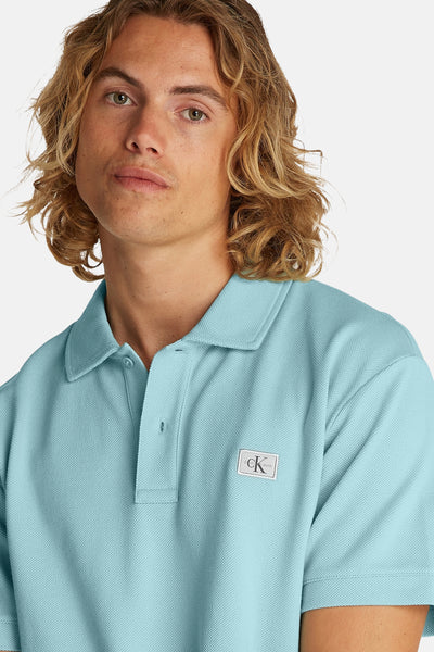 Turquoise poloshirt met korte mouwen van Calvin Klein, pique textuur, logo-embleem op de borst, één zichtbare knoop.