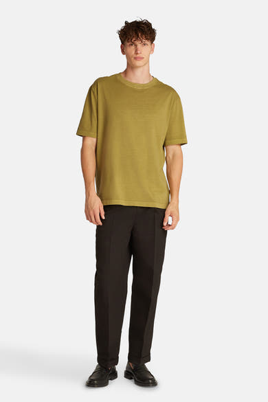 Okerkleurig T-shirt met korte mouwen van Calvin Klein, gedragen met een zwarte broek en loafers.