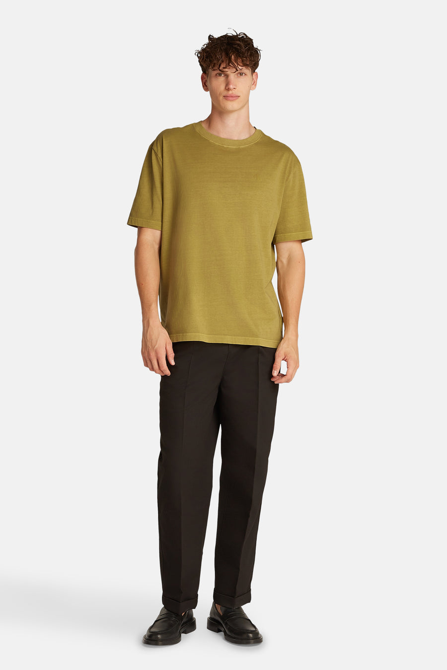 Okerkleurig T-shirt met korte mouwen van Calvin Klein, gedragen met een zwarte broek en loafers.