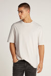 Ecru T-shirt met korte mouwen van Calvin Klein, gedragen met een zwarte, uitgewassen spijkerbroek, model kijkt naar links.