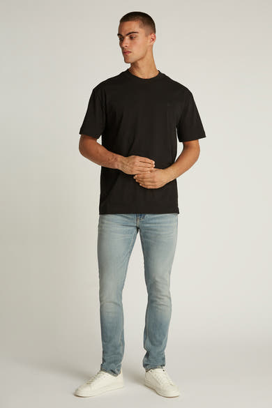 Zwart T-shirt met korte mouwen van Calvin Klein, gedragen met een verbleekte spijkerbroek en witte sneakers.