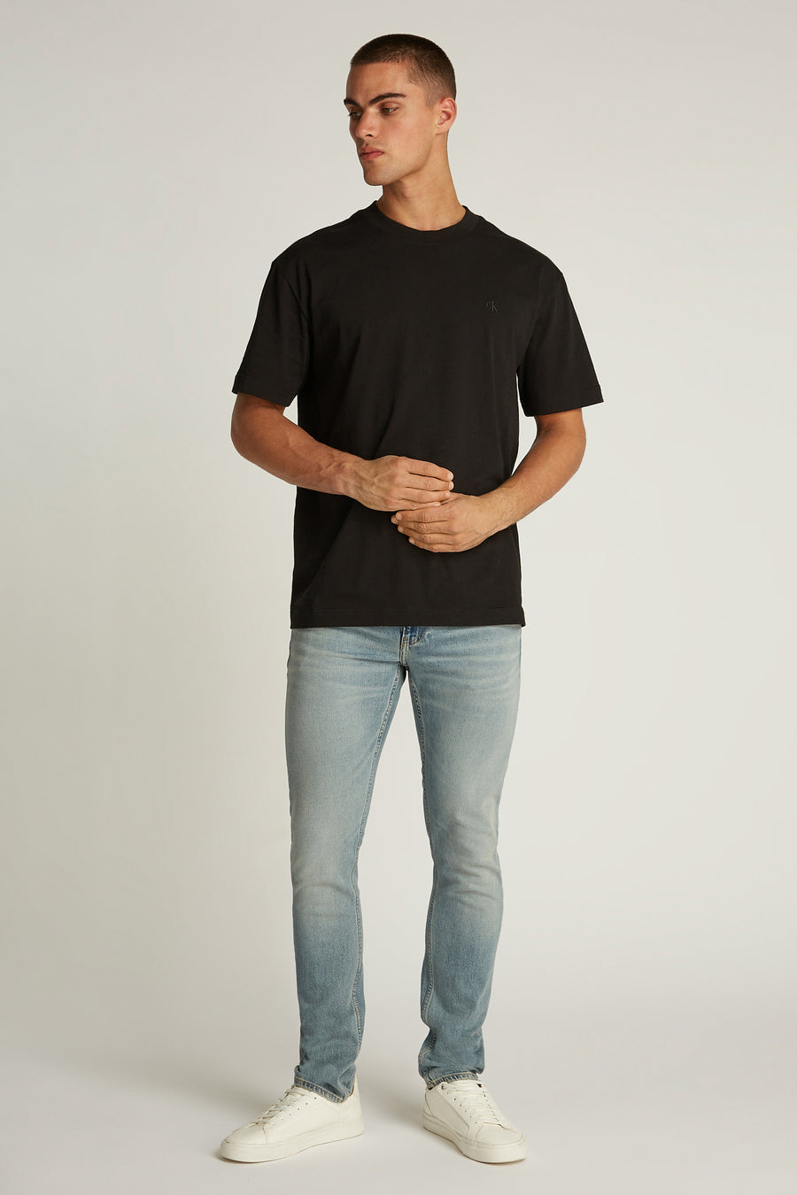 Zwart T-shirt met korte mouwen van Calvin Klein, gedragen met een verbleekte spijkerbroek en witte sneakers.