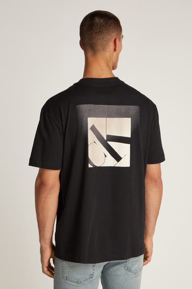 Zwart T-shirt met korte mouwen van Calvin Klein, met vierkant grafisch patroon op de rug, gedragen met een spijkerbroek.