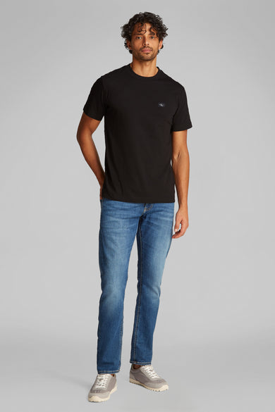 Zwart T-shirt met korte mouwen van Calvin Klein, gedragen met een blauwe spijkerbroek en grijze sneakers.
