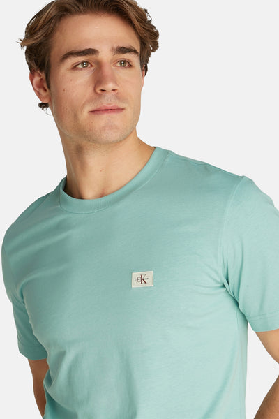 T-shirt turquoise à manches courtes de Calvin Klein, uni avec logo carré sur la poitrine.
