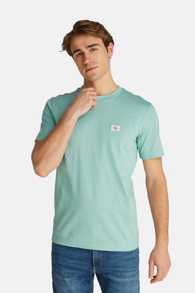 Turquoise T-shirt met korte mouwen van Calvin Klein, gedragen met een blauwe spijkerbroek.
