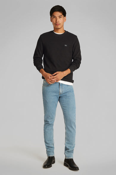 T-shirt à manches longues noir de Calvin Klein, porté avec un jean bleu et des bottes noires.
