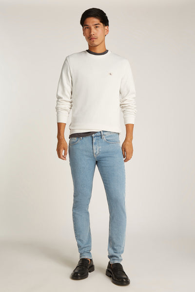 T-shirt écru à manches longues de Calvin Klein, porté avec un jean bleu et des mocassins noirs.