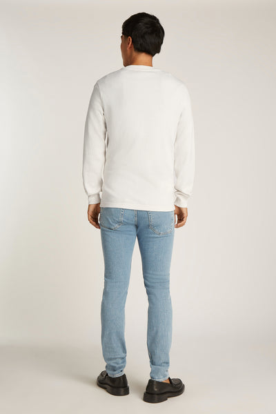 T-shirt à manches longues écru de Calvin Klein, porté avec un jean bleu clair et des mocassins noirs, vue de dos.
