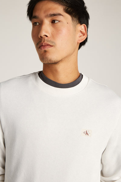 Ecru T-shirt met lange mouwen van Calvin Klein, met discreet logo en zichtbare grijze ronde hals.