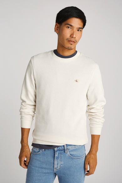 T-shirt écru à manches longues de Calvin Klein, porté avec un jean bleu clair