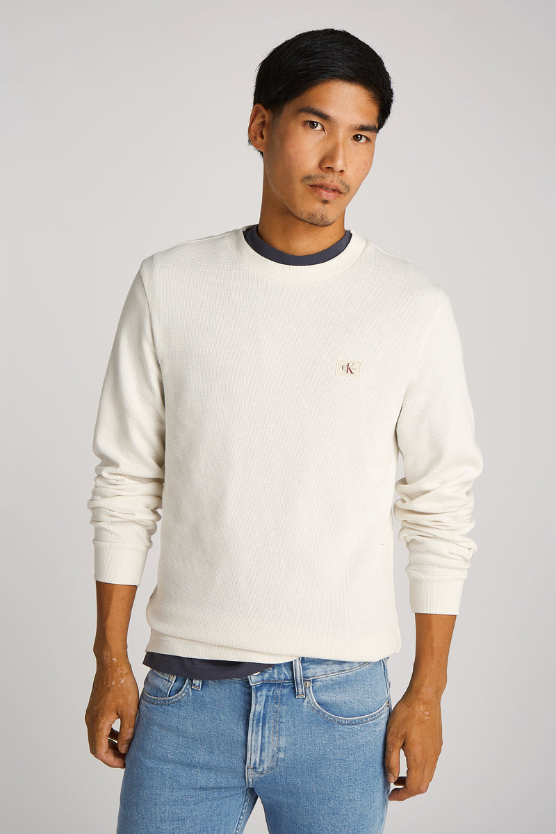 T-shirt écru à manches longues de Calvin Klein, porté avec un jean bleu clair