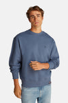 Sweat-shirt bleu encolure ronde de Calvin Klein, avec un petit logo sur le devant et porté avec un jean clair.