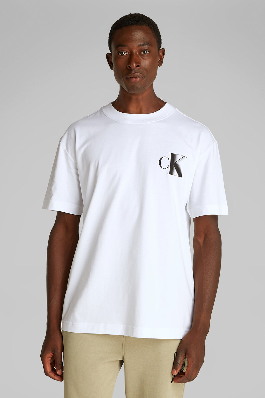 Wit T-shirt met korte mouwen van Calvin Klein, met logo op de voorkant, gedragen met een beige broek.
