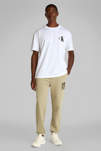 Wit T-shirt met korte mouwen van Calvin Klein, met zwart logo op de voorkant, gedragen met een beige broek.