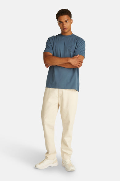 Blauw T-shirt met korte mouwen van Calvin Klein, met toon-op-toon logo op de borst, gedragen met een beige broek en witte sneakers.