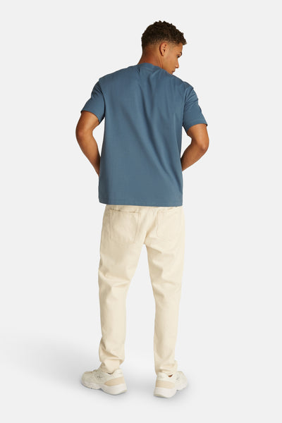 Blauw T-shirt met korte mouwen van Calvin Klein, gedragen met een beige broek en witte sneakers, achtergezicht.