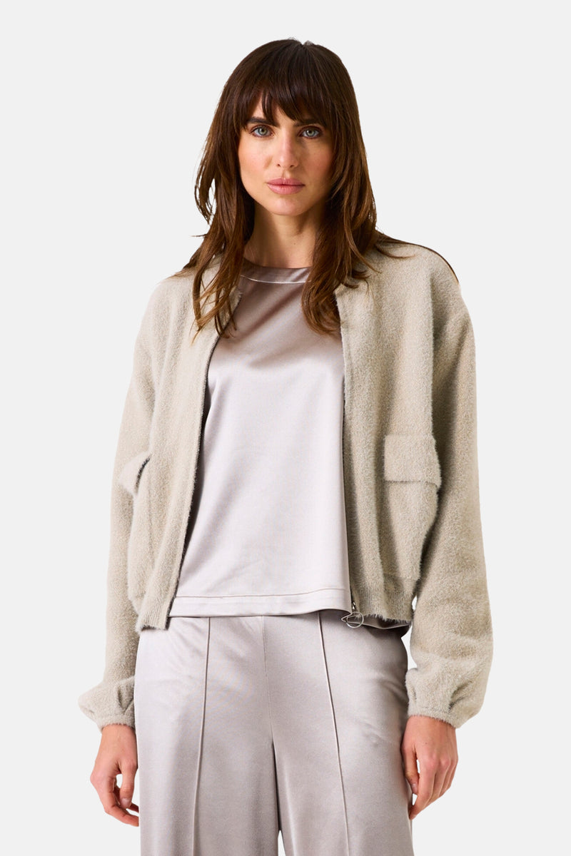 Gilet beige en maille duveteuse de GARCIA, porté sur un haut satiné et un pantalon coordonné.
