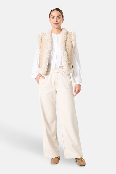 Beige fauxbontjas van GARCIA, gedragen over een wit overhemd en een broek met hoge taille.