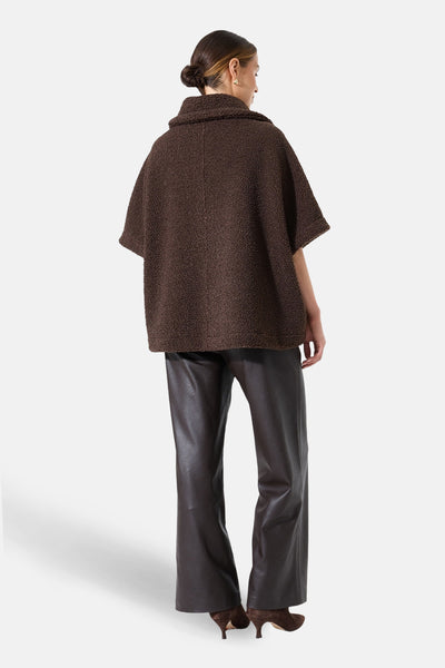 Bruine jas van bouclé stof van GARCIA, van achteren getoond, gedragen met een imitatielederen broek en bruine pumps.