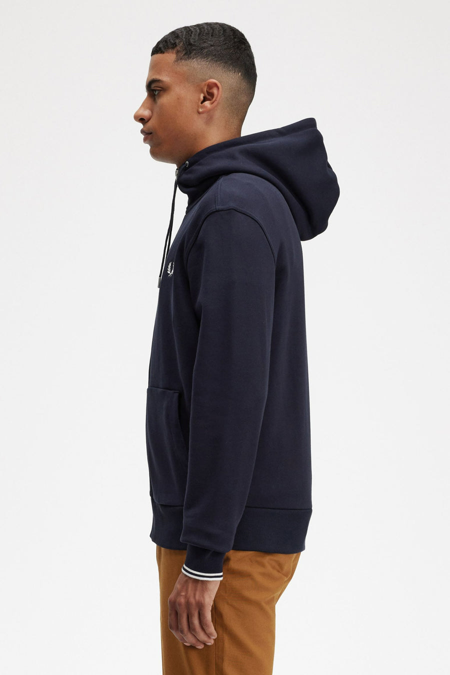 Marineblauwe hoodie van FRED PERRY, met trekkoord en kangoeroezak, gedragen met een bruine broek.