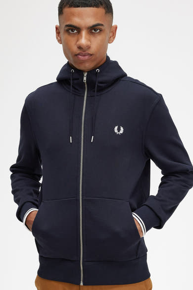 Blauwe FRED PERRY bodywarmer, met ritssluiting, capuchon, zakken en gestreepte details op de manchetten.