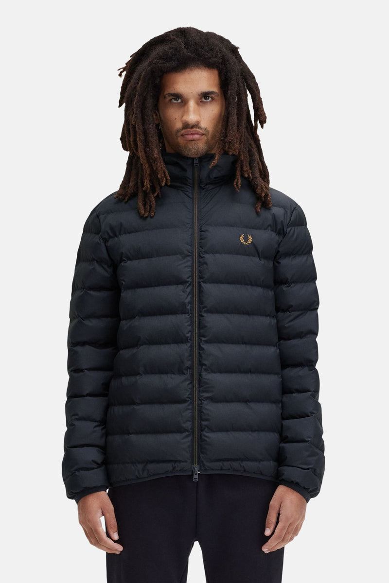 Zwarte regenjas van FRED PERRY, gewatteerd met ritssluiting en gouden logo, gedragen met een zwarte broek.