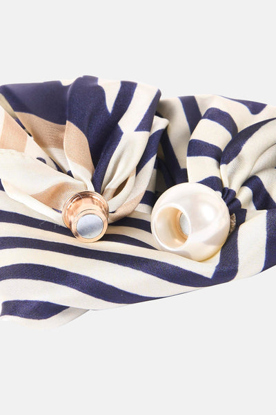 Beige foulard with navy and cream striped pattern, featuring rose gold and pearl embellishments, close-up view