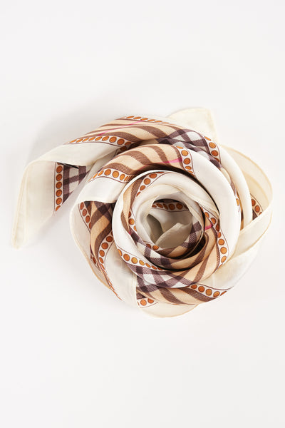 Beige foulard with brown and white check pattern and orange dot border, coiled on white background
