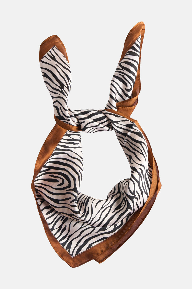 Bruine sjaal van Access® met zwart-wit zebraprint, geknoopt en vormend als konijnenoren.