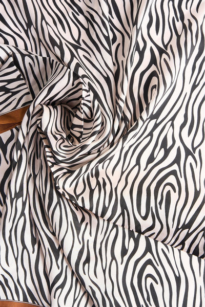 Bruine Access® sjaal, opgerold met zebraprint, met een zichtbare bruine rand.