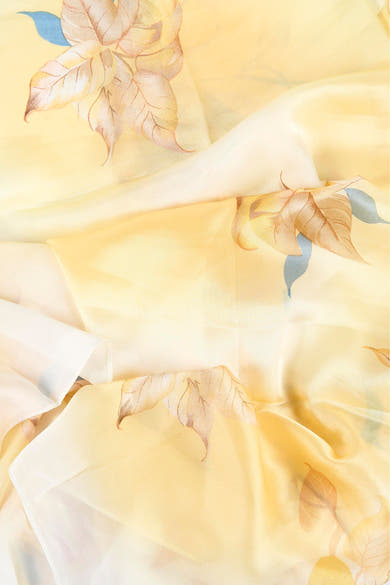 Foulard jaune fluide de Access® orné de motifs de feuilles beiges et bleues, drapé.