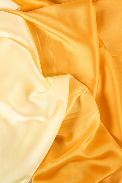 Foulard jaune Access® en tissu soyeux, avec des plis élégants et des nuances de couleur chaude.