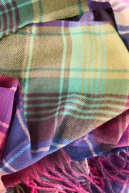 Gros plan sur un foulard Access® multicolore à carreaux, avec des franges.