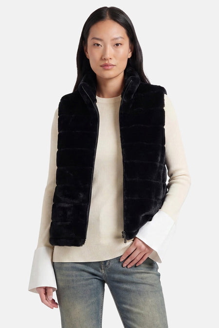 Veste sans manches noire en fausse fourrure de Access®, à col montant zippé, portée sur un pull crème et un jean.