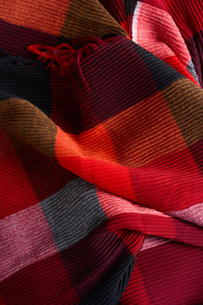 Écharpe rouge à carreaux par Access®, avec des motifs texturés et des détails de franges.
