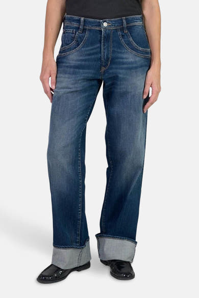 Jean large en denim bleu foncé par Le Temps des Cerises, avec revers et chaussures vernies noires.
