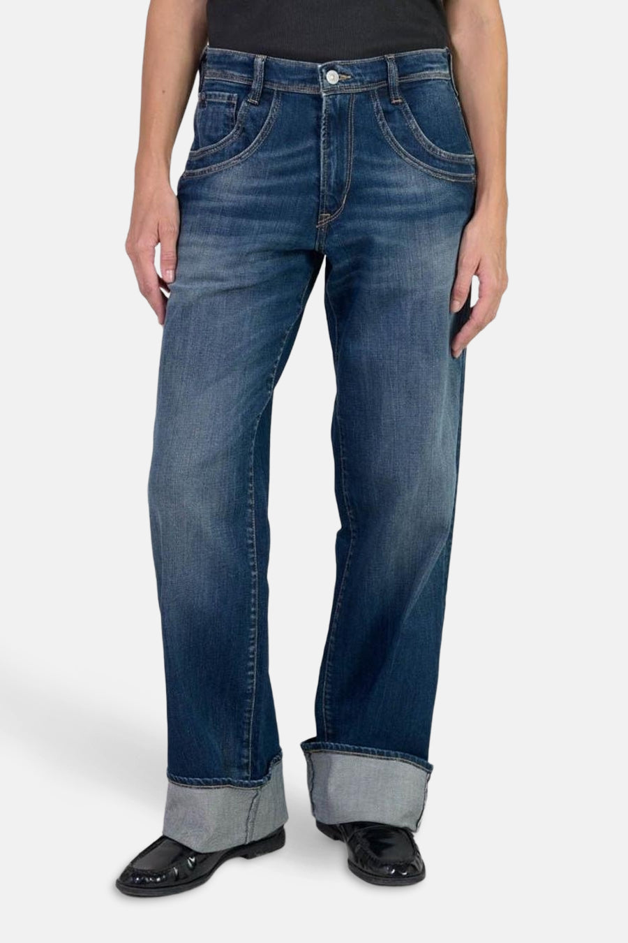 Jean large en denim bleu foncé par Le Temps des Cerises, avec revers et chaussures vernies noires.
